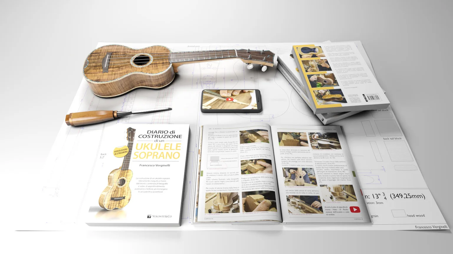 Il volume "Diario di costruzione di un ukulele soprano" aperto sul banco accanto a un ukulele e ai disegni tecnici